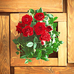 Image showing red roses on a wooden table