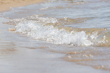 Image showing A small sea wave rolls on sandy beach, close-up