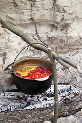 Image showing Soup cooking in sooty cauldron on campfire 