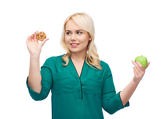 Image showing smiling woman choosing between apple and cookie