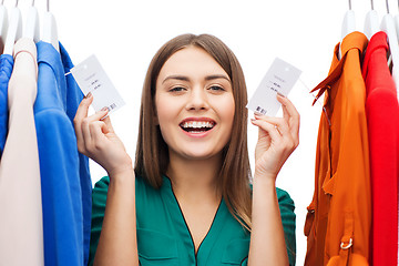 Image showing happy woman with sale tags on clothes at wardrobe