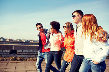 Image showing happy teenage friends walking along city street