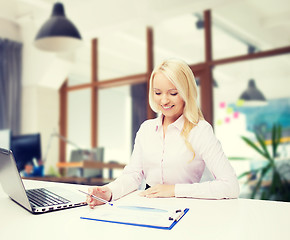 Image showing smiling businesswoman reading papers in office