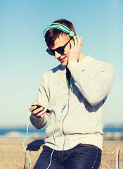 Image showing happy young man in headphones with smartphone