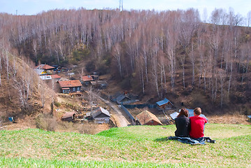 Image showing Young romantic couple sits on hill over downtown