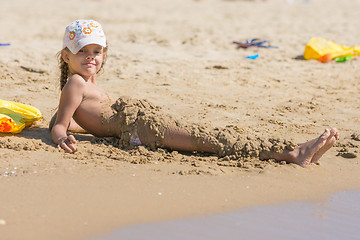 Image showing Child falls asleep with wet sand lying on the beach