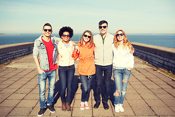 Image showing smiling teenagers in sunglasses hugging on street