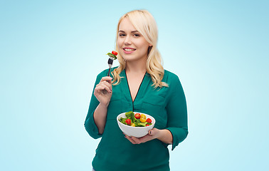 Image showing smiling young woman eating vegetable salad