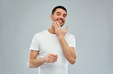 Image showing happy young man applying cream or lotion to face