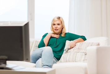 Image showing smiling woman with remote watching tv at home