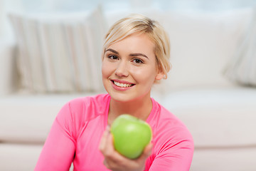 Image showing happy woman eating green apple at home