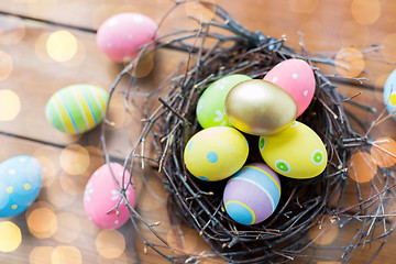 Image showing close up of colored easter eggs in nest on wood