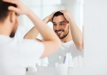 Image showing happy young man looking to mirror at home bathroom