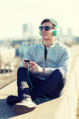 Image showing happy young man in headphones with smartphone