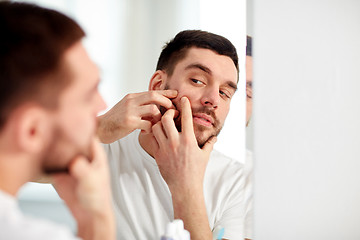 Image showing man squeezing pimple at bathroom mirror