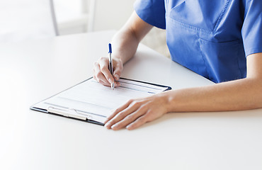 Image showing close up of doctor or nurse writing to clipboard