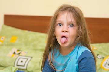 Image showing Five-year girl waking up sitting on the bed and showing tongue