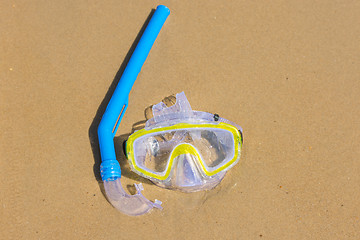 Image showing The swimming mask and snorkel to breathe under water, lie on the wet sand at the sea coast