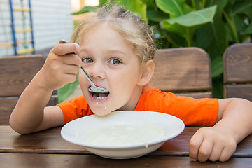 Image showing Five-year girl with pleasure eats porridge for breakfast