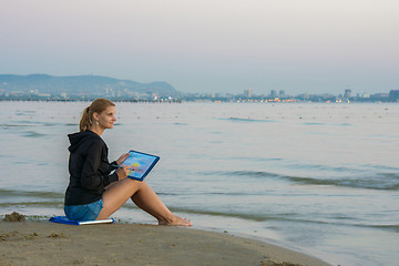 Image showing Young girl sitting on the beach and drawing landscape with sunset