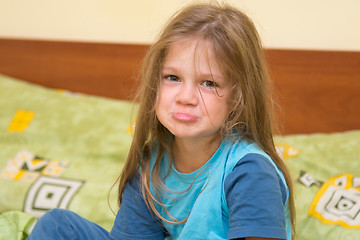 Image showing Five-year girl waking up sitting on the bed and looks ridiculous in the frame