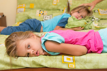 Image showing Two girls lie on a bed on the opposite sides