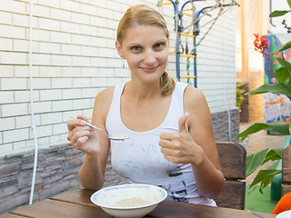 Image showing Twenty-five girl eating cereal breakfast on the veranda and shows class