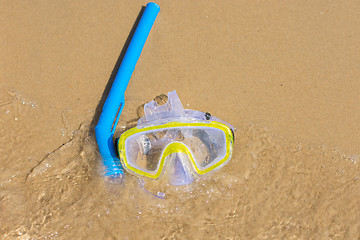 Image showing The swimming mask and snorkel to breathe under water, lie on the sand at the waters edge