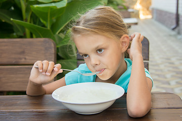 Image showing Upset six year old girl slowly eating porridge for breakfast