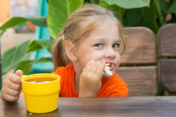 Image showing Hungry funny girl biting bun and drinking tea