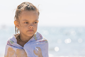 Image showing Up portrait of five year old girl wrapped in a towel on the background of the sea