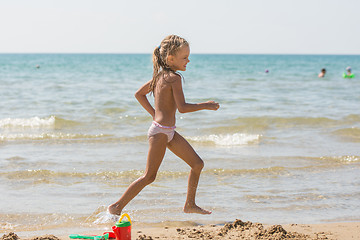 Image showing Five-year girl runs along the shore of the beach at the seaside