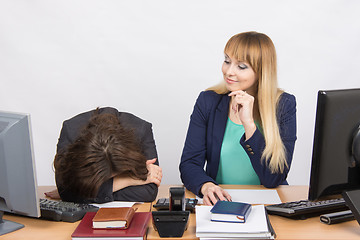 Image showing The situation in office - frustrated woman lay on the table, her colleague looking at her haughtily