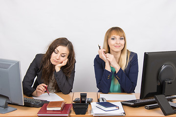 Image showing The situation in the office - a woman upset looking at the document, the other happily looks into the frame