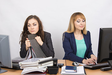Image showing Female colleagues in the office, a tired looking in the monitor, the other happy working on a computer