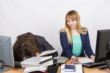 Image showing Female colleagues in the office, one had fallen asleep on a pile of folders, and the second looked at her