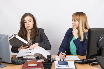 Image showing The situation in the office - one employee overburdened, the other does nothing and laughs looking at her