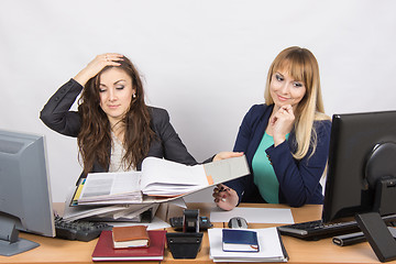 Image showing The situation in the office - one employee watching folders with documents and clutched her head, and the second looks at laptop