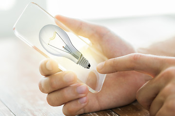 Image showing close up of hand with light bulb on smartphone