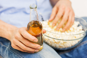 Image showing close up of man with popcorn and beer at home