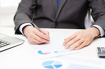 Image showing close up of businessman hand with charts in office
