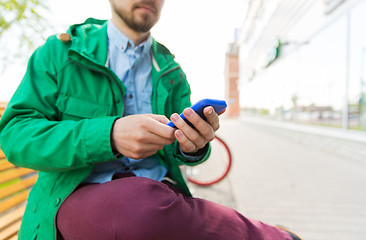 Image showing close up of man with smartphone sitting on bench