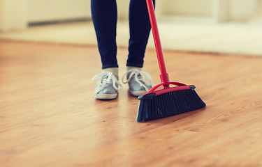 Image showing close up of woman legs with broom sweeping floor