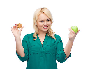 Image showing smiling woman choosing between apple and cookie