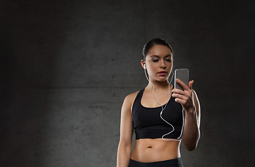 Image showing woman with smartphone and earphones in gym