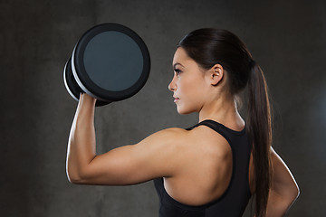 Image showing young woman flexing muscles with dumbbells in gym