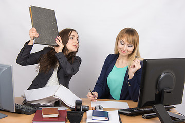 Image showing The girl in the office threatens to hit another folder employee