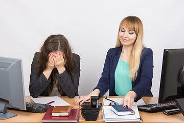 Image showing The situation in the office - one girl is very upset, others are pretty straightens things on your desktop