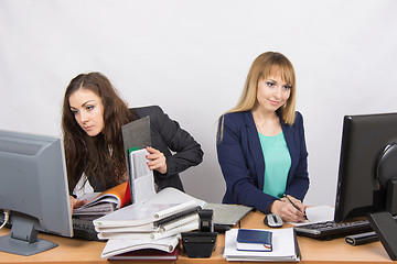 Image showing Colleagues in the office Girls, both looking to the first monitor with a bunch of papers and folders, second only to the sheet of paper