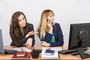 Image showing The situation in the office - one employee on the phone, the other asks for her phone